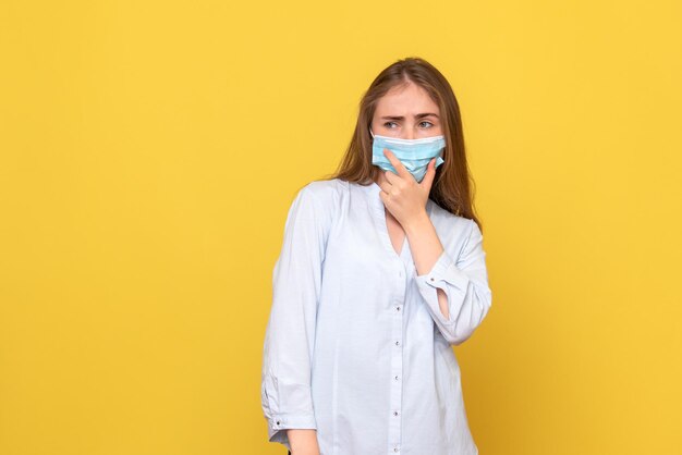 Front view of young woman thinking on yellow wall