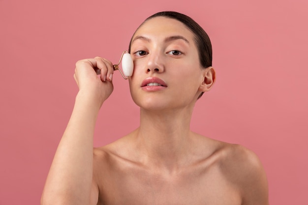 Front view young woman using face roller