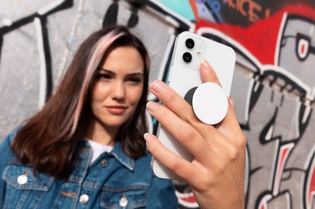 Бесплатное фото Вид спереди молодая женщина с помощью popsocket