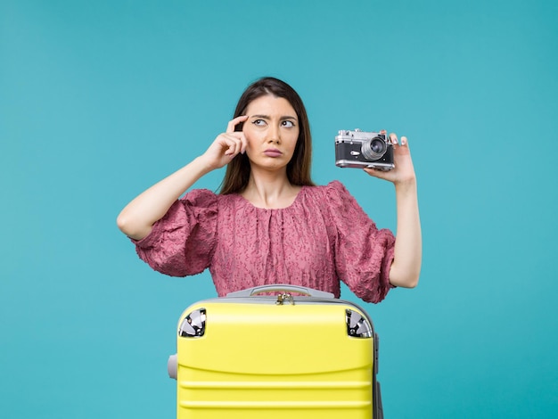 Вид спереди молодая женщина в отпуске, держащая фотоаппарат на синем столе, путешествие на море, женщина за границей, отпуск