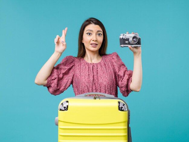 青い背景の旅の海の旅の女性海外休暇でカメラで写真を撮る休暇中の若い女性の正面図
