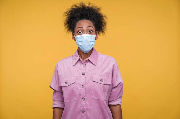 Free photo front view of a young woman wearing a medical mask and looking surprised