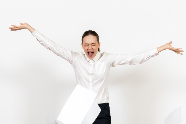 Вид спереди молодая женщина в белой блузке, сердито бросая файлы на белом фоне, женские эмоции, чувствуя офисную работу