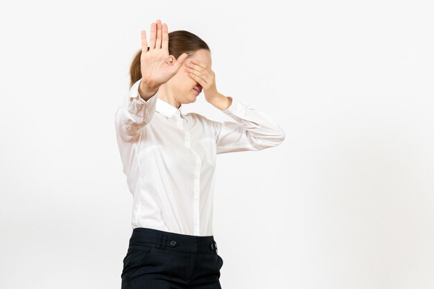 Front view young woman in white blouse covering her face on a white background office job female emotion feeling model