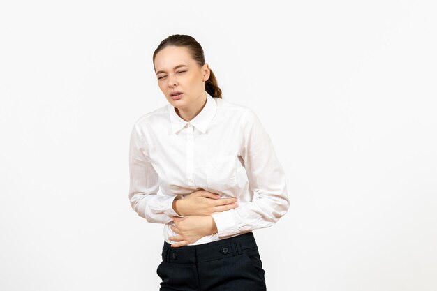 白い背景に胃痛を持っている白いブラウスの正面図若い女性オフィスの仕事女性の感情感モデル