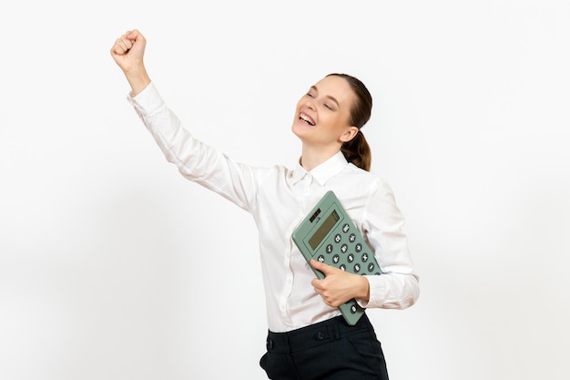 Vista frontale giovane donna in camicetta bianca che tiene calcolatrice su sfondo bianco lavoratore emozione femminile lavoro d'ufficio bianco