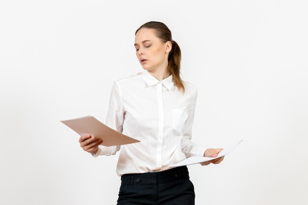 Вид спереди молодая женщина в белой блузке, держащая и проверяющая документы на белом фоне, женская работа, эмоции, чувство модельного офиса