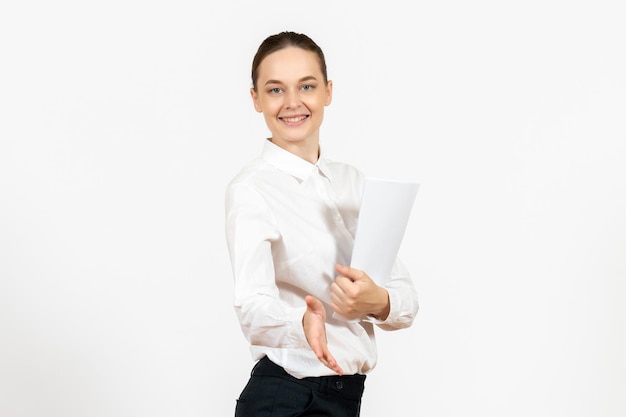 Вид спереди молодая женщина в белой блузке, держащая документы и улыбающаяся на белом фоне, женские эмоции, чувствуя офисную работу