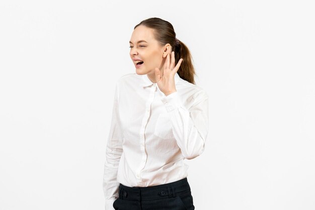 Вид спереди молодая женщина в белой блузке, внимательно слушающая на белом фоне, женский офис, эмоция, работа, чувство, модель