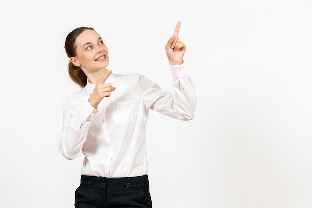 Вид спереди молодая женщина в белой блузке, указывая и улыбаясь на белом фоне, работа в офисе, женские чувства, модель эмоции