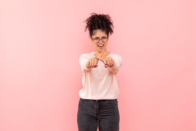 Front view of young woman with angry expression on pink wall