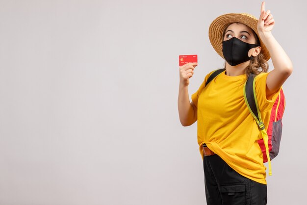 Front view young woman with backpack holding up card pointing finger up