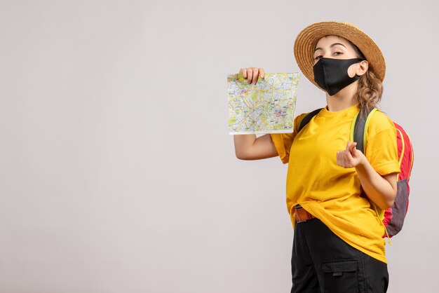 Front view young woman with backpack holding up map making money sign