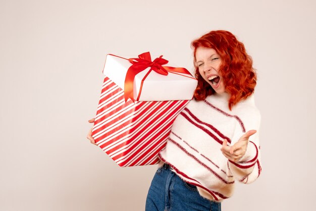 Front view of young woman with big present on the white wall