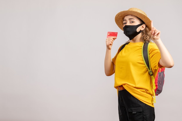 Front view young woman with black mask and backpack holding card