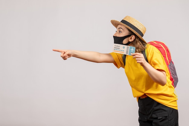 Free Photo front view young woman with black mask holding travel ticket pointing at left