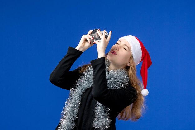 Front view of young woman with camera on a blue wall