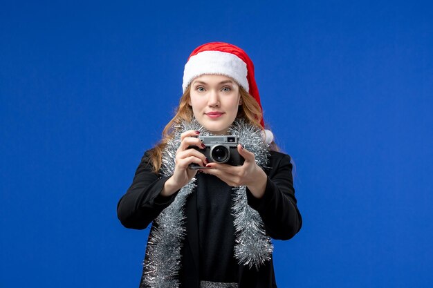 青い壁にカメラを持つ若い女性の正面図