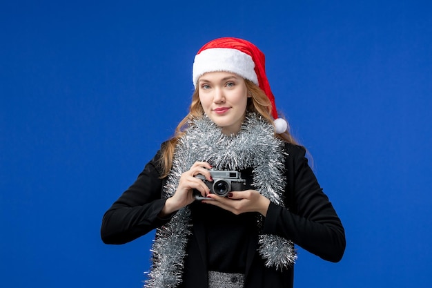 青い壁にカメラを持つ若い女性の正面図
