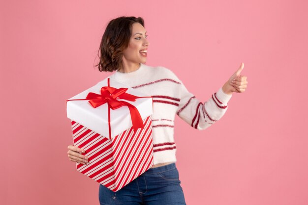 Vista frontale della giovane donna con regalo di natale sulla parete rosa