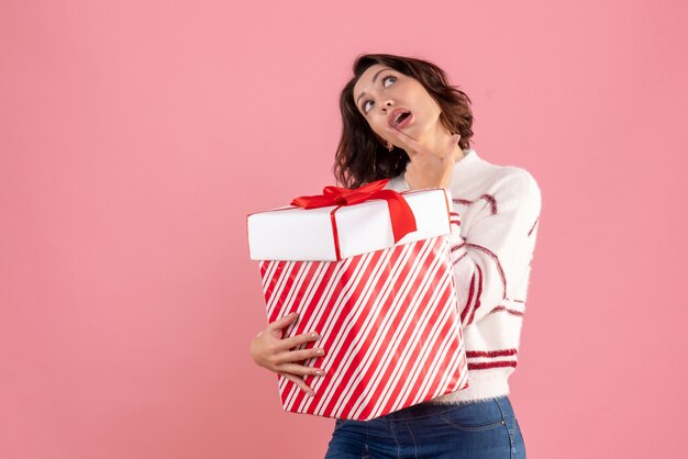 Front view of young woman with christmas present on pink wall