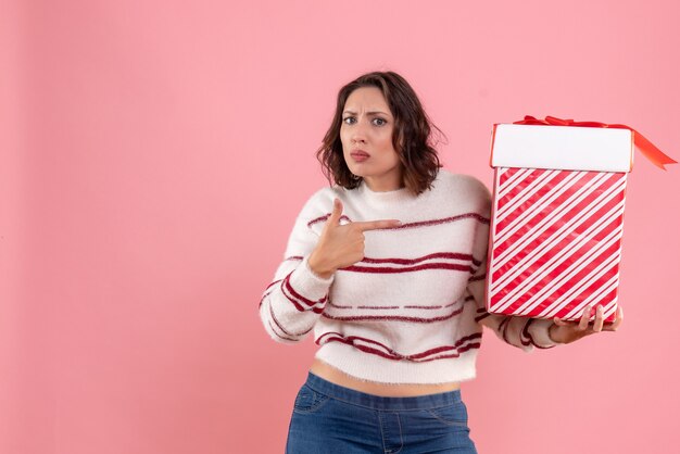 ピンクの壁にクリスマスプレゼントと若い女性の正面図