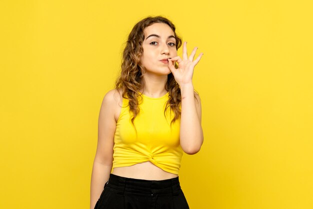 Front view of young woman with delighted expression on yellow wall