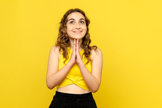 Front view of young woman with excited expression on yellow wall