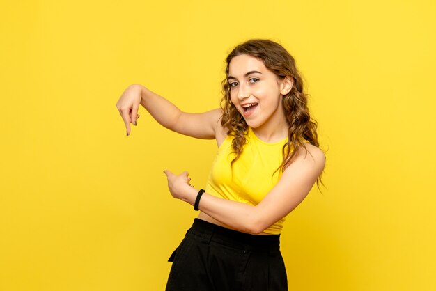 Front view of young woman with excited face on yellow wall