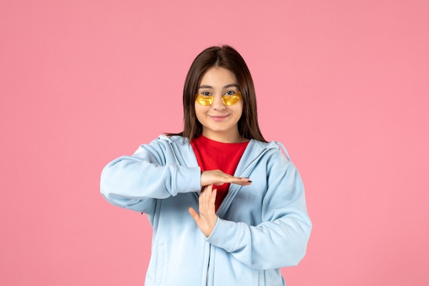 Free photo front view of young woman with eye patches under her eyes on pink wall