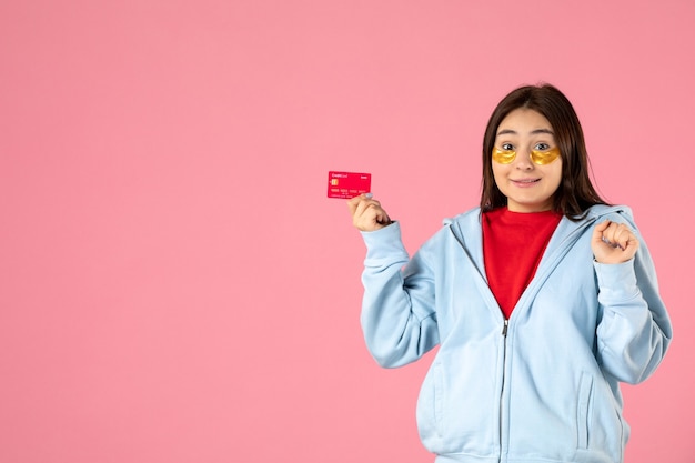 Free photo front view of young woman with eye patches holding bank card on pink wall