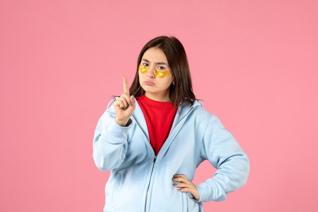 front view of young woman with eye patches on pink wall