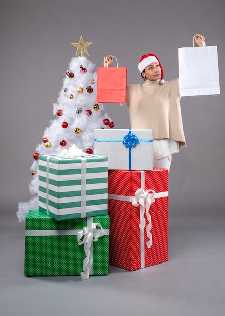 Front view young woman with holiday presents on grey desk xmas new year gift