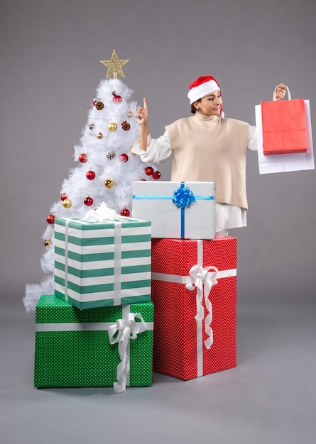 Front view young woman with holiday presents on grey