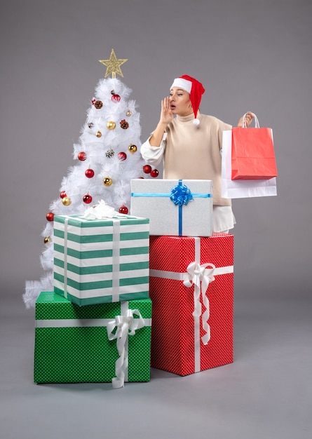 Front view young woman with holiday presents on grey