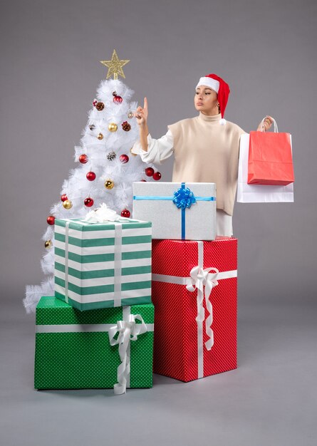 Front view young woman with holiday presents on grey