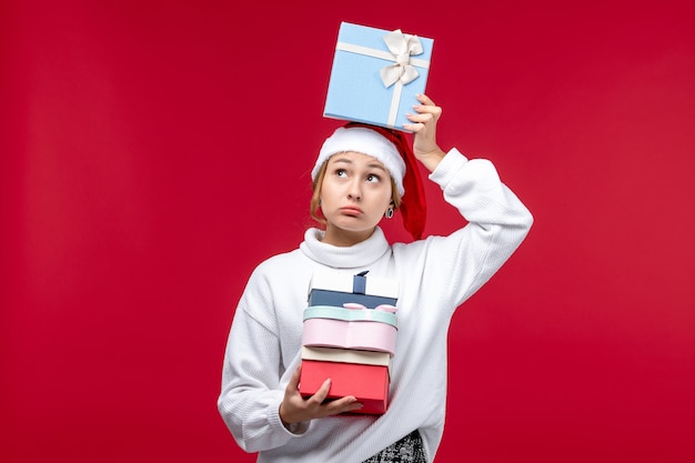 Front view young woman with holiday presents on the red background