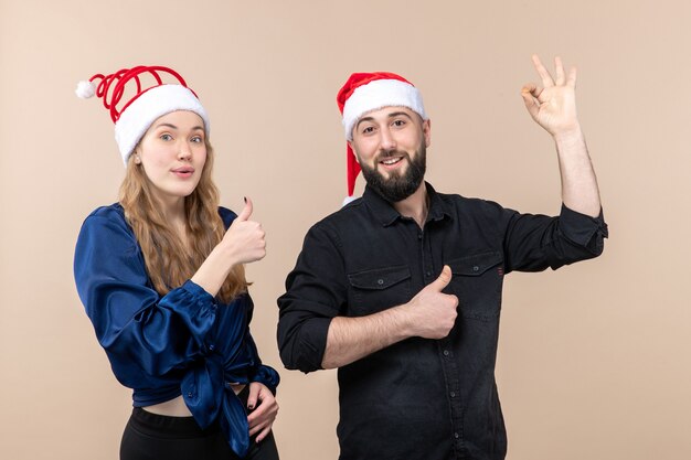 Front view of young woman with man expressing different emotions on pink wall