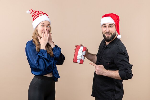 Front view of young woman with man who's giving her a present on a pink wall