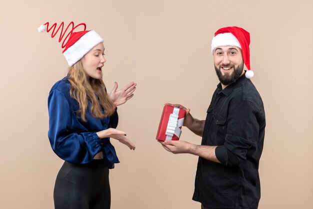 Front view of young woman with man who's giving her a present on pink wall