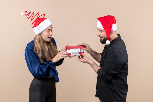 Front view of young woman with man who's giving her a present on pink wall