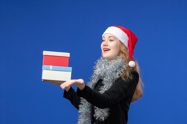 Free photo front view of young woman with new year's presents on blue wall