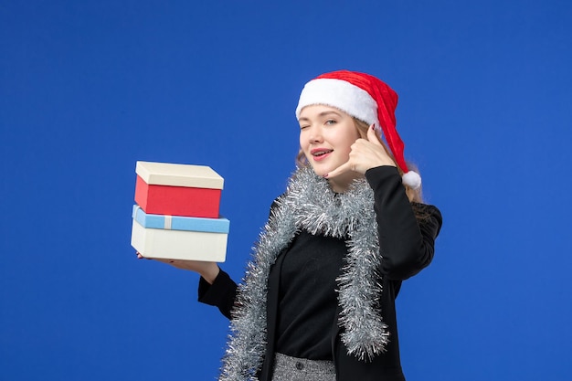 Free photo front view of young woman with new year's presents on blue wall