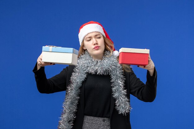 Front view of young woman with New Year's presents on blue wall