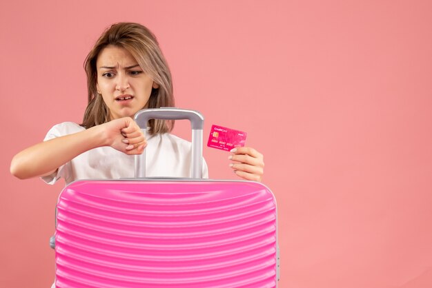 Front view young woman with pink suitcase holding map checking time