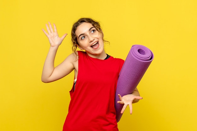 Front view of young woman with purple carpet on the yellow wall