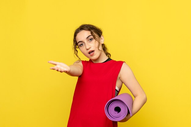 Front view of young woman with purple carpet on yellow wall