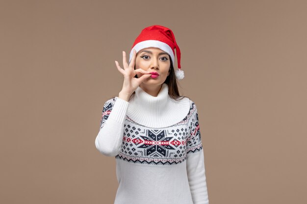 正面図茶色の背景に赤いクリスマスキャップを持つ若い女性クリスマス感情新年