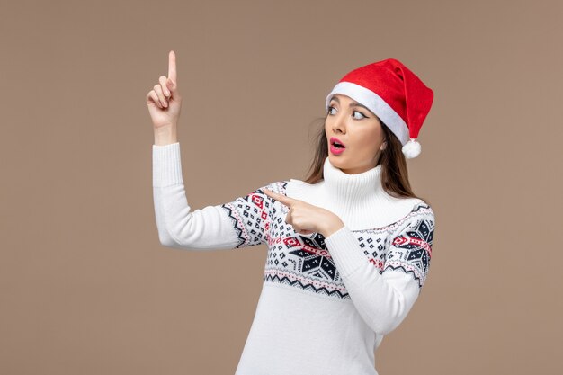 Вид спереди молодая женщина с красной рождественской шапкой на коричневом фоне рождественские эмоции новый год