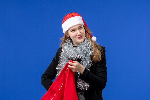 Front view of young woman with red present bag on blue wall